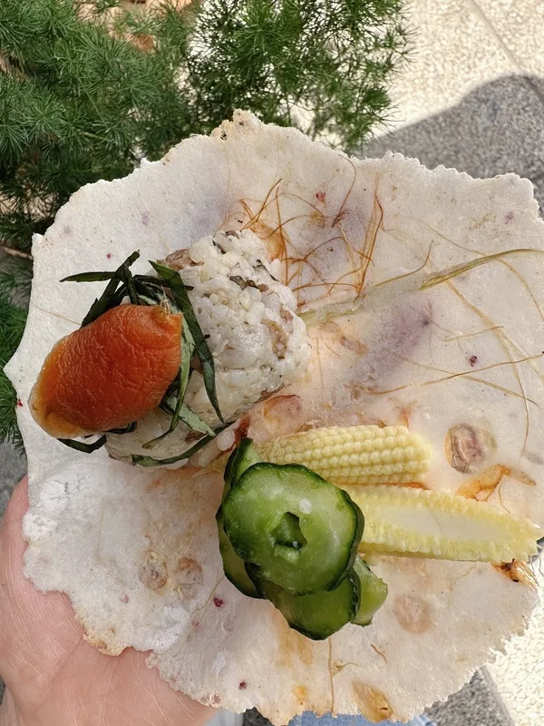 創意綠色飯擔「彩虹玉米仙貝飯糰」，盛裝器皿採用在地越光米和彩虹玉米研磨、低溫烘焙製成，完全可食。綠色餐飲指南提供