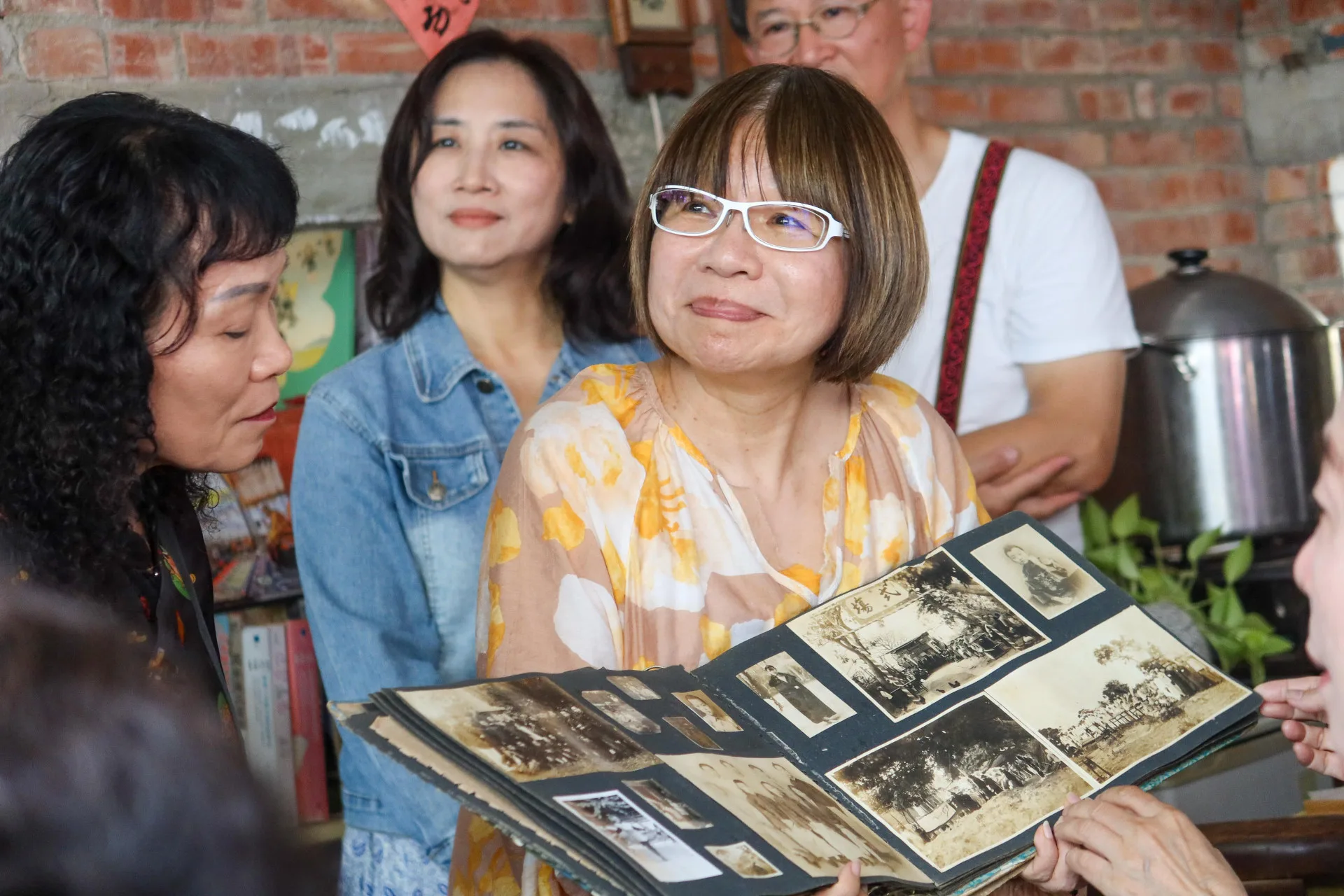 張典婉在新書發表會上捧著林家歷史照片，讓林紅炎解說林家歷史滄桑。何來美攝