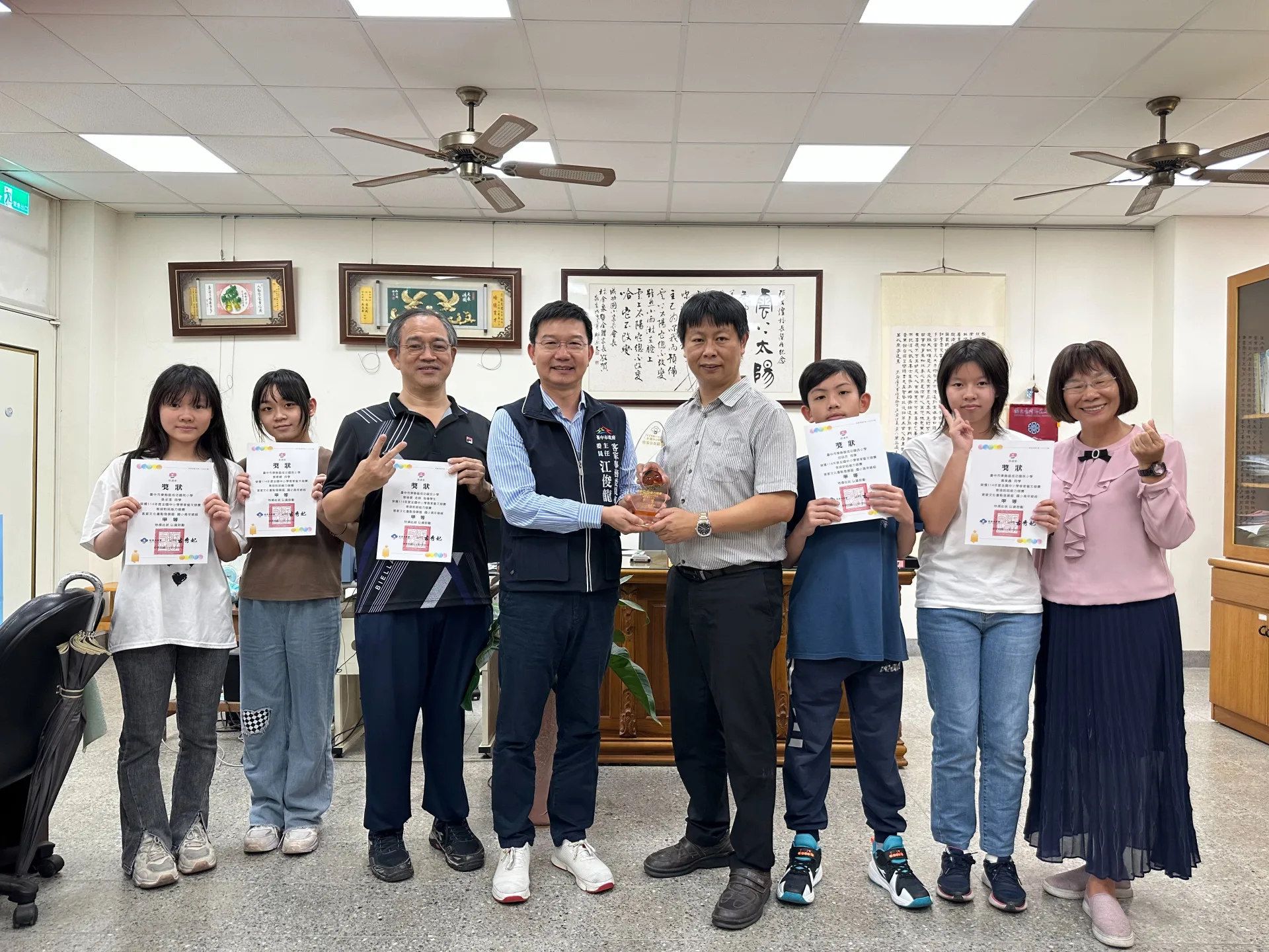 中市府客委會主委江俊龍26日親送獎座和獎狀到東勢區成功國小。