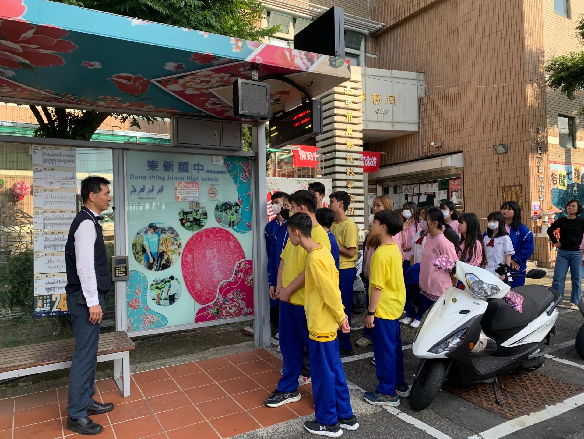 東新國中學生在客家花布浪漫候車亭跟「東新國中」同名站牌合影。台中市政府提供