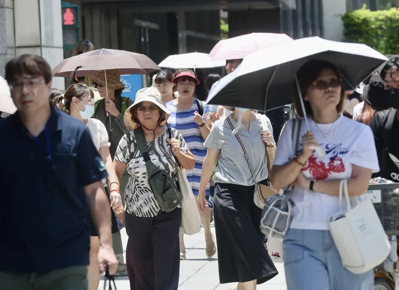 天氣晴朗炎熱，大台北等縣市注意攝氏36度以上高溫。圖為台北市中正區民眾撐傘防曬。中央社