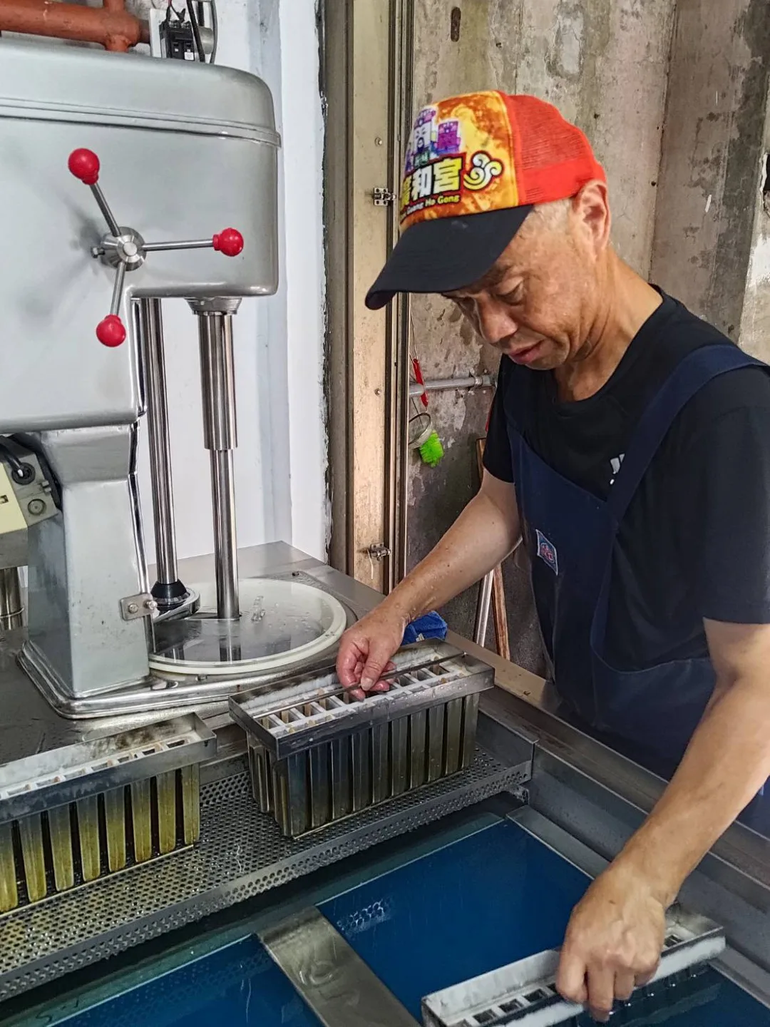 身穿殺魚圍裙的陳智弘將模具浸入冷劑中,一旁是製作綿綿冰的攪拌機。陳智弘提供