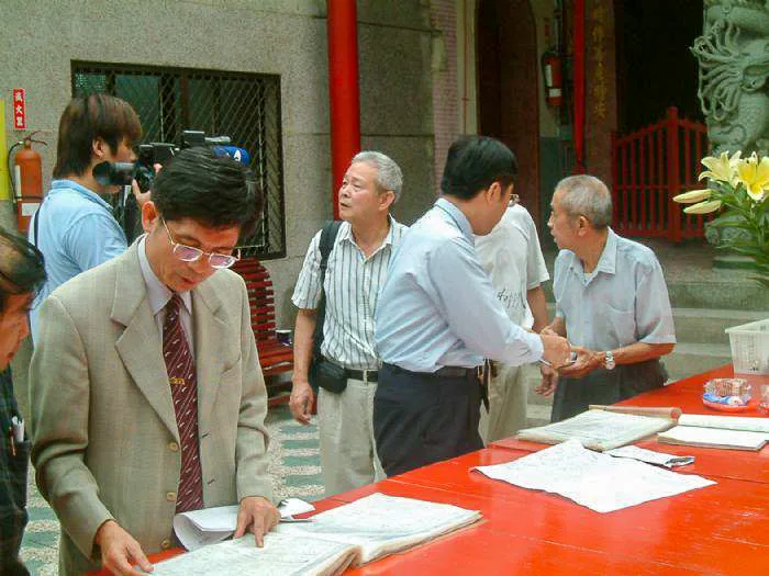 圖說:王塗發（左）從厚厚的名冊中，仔細翻閱，只花半小時就找到父親名字。圖中背對鏡頭者是黃偉哲。陳權欣攝