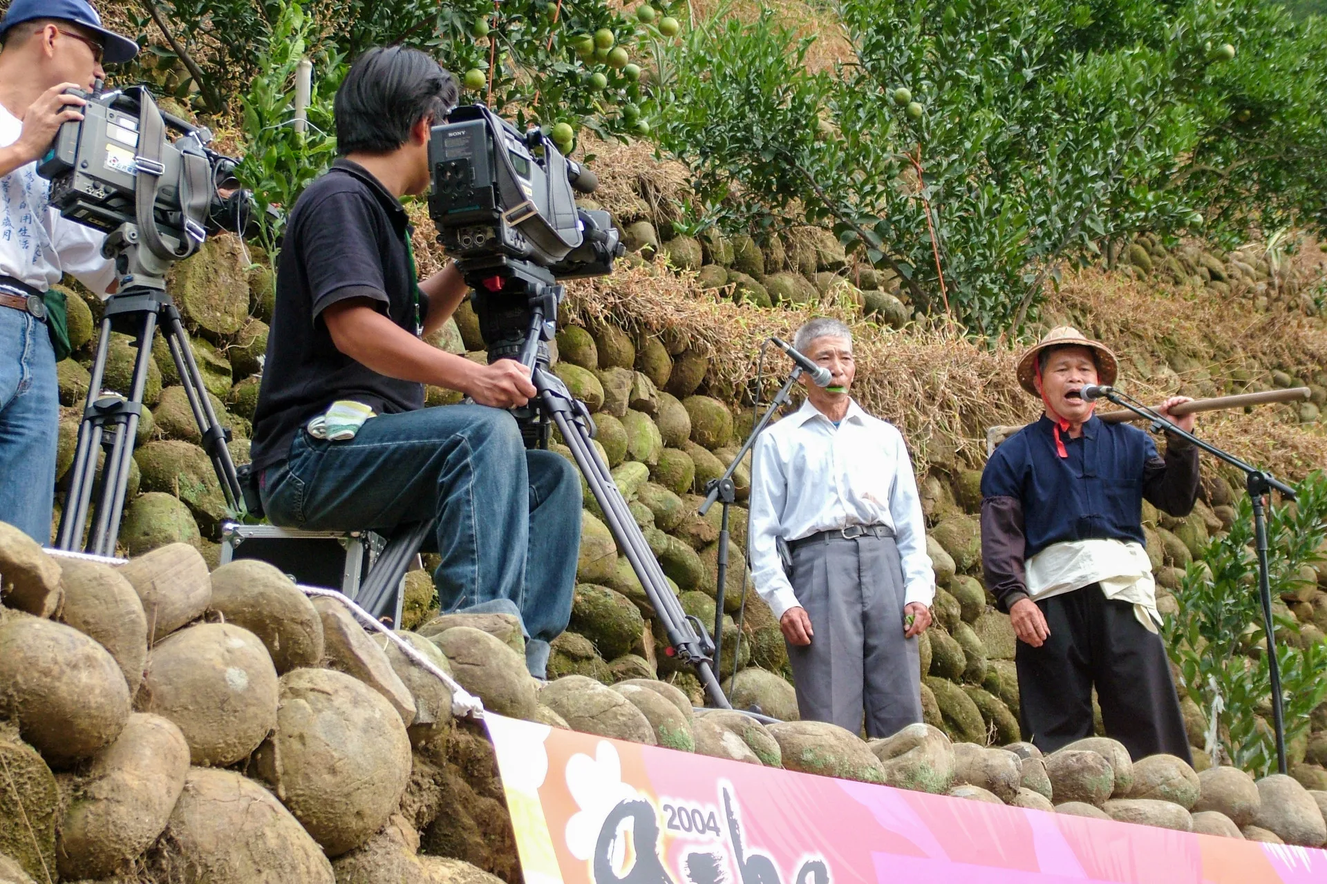 山歌大師林德富，他在模仿原生態山歌，這是他（右一）在鹿寮坑地景音樂會演唱神情，當時客委會主委羅文嘉還到場給他鼓勵，這是表演式山歌，也是一種衍生態山歌。楊國鑫攝