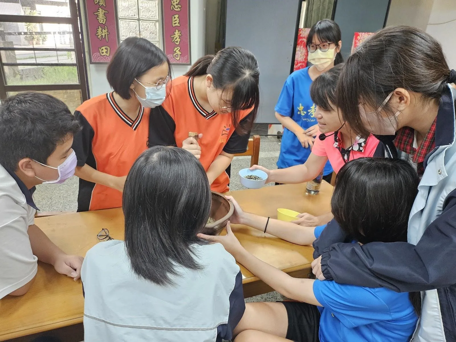 台南忠孝國中學生製作擂茶，合力把材料磨成粉末，還能夠邊「打嘴鼓」。客委會提供