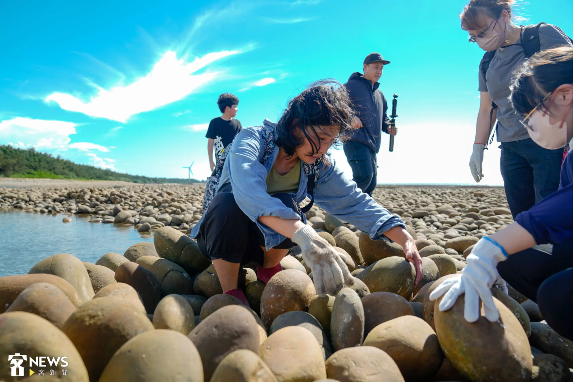 導覽員示範撿拾小石頭塞進縫隙，維護石滬的構造穩固。朱愷元攝