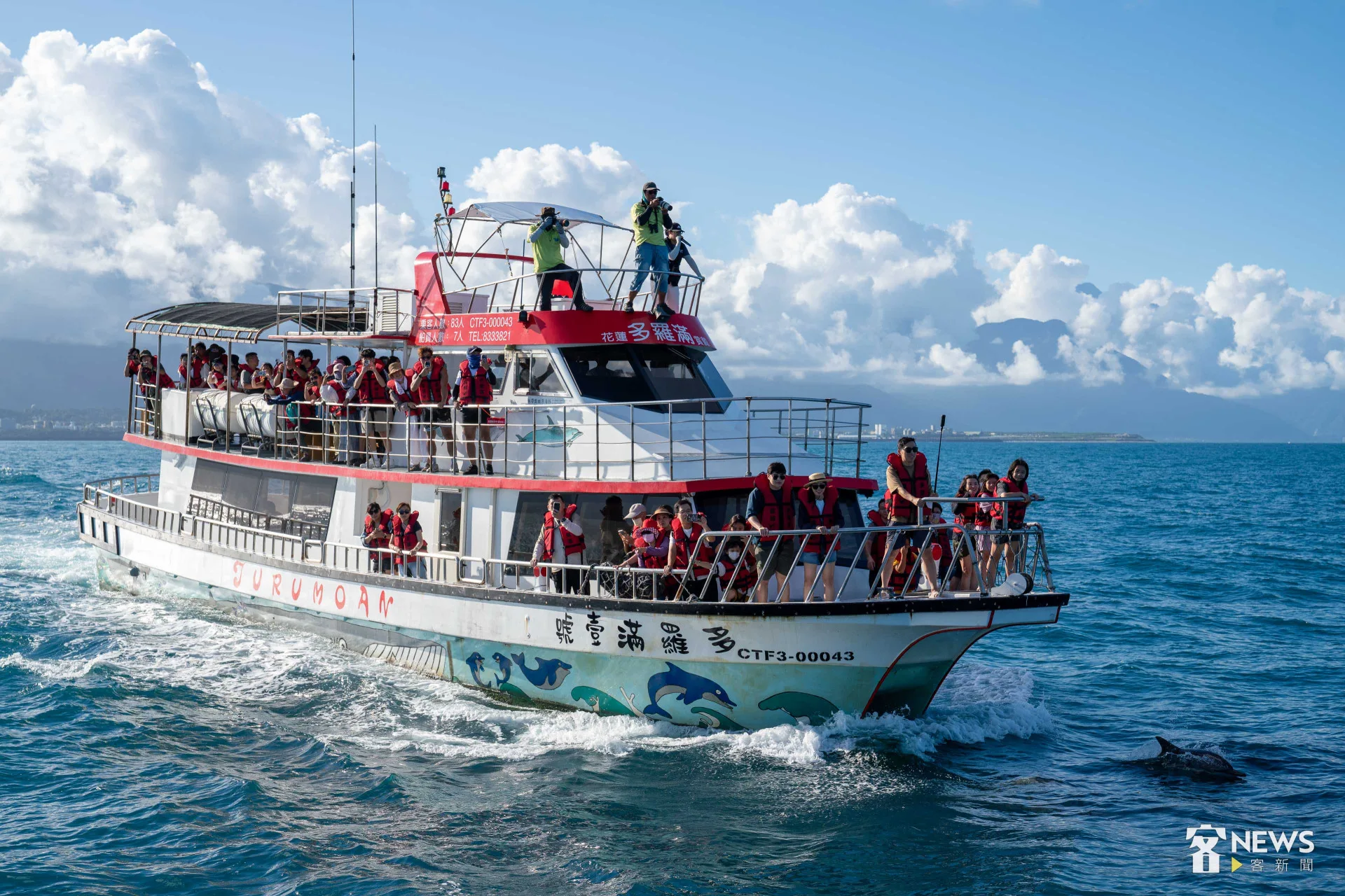 與客語航班同行的賞鯨船，旅客或坐或站，在船舷欣賞飛旋海豚的英姿。李台源攝