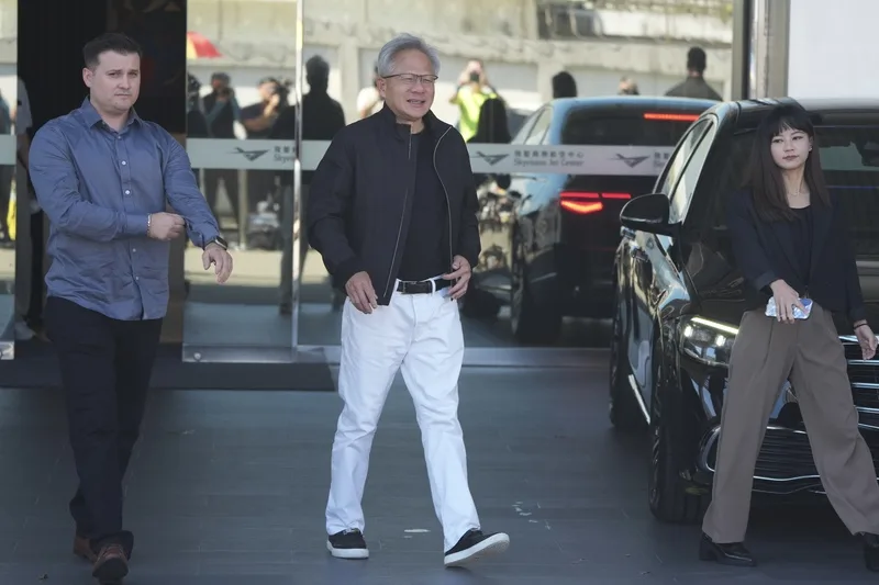 輝達（NVIDIA）執行長黃仁勳（中）22日上午無預警訪台，身穿黑夾克搭配白褲，輕鬆地步出松山機場商務中心。中央社