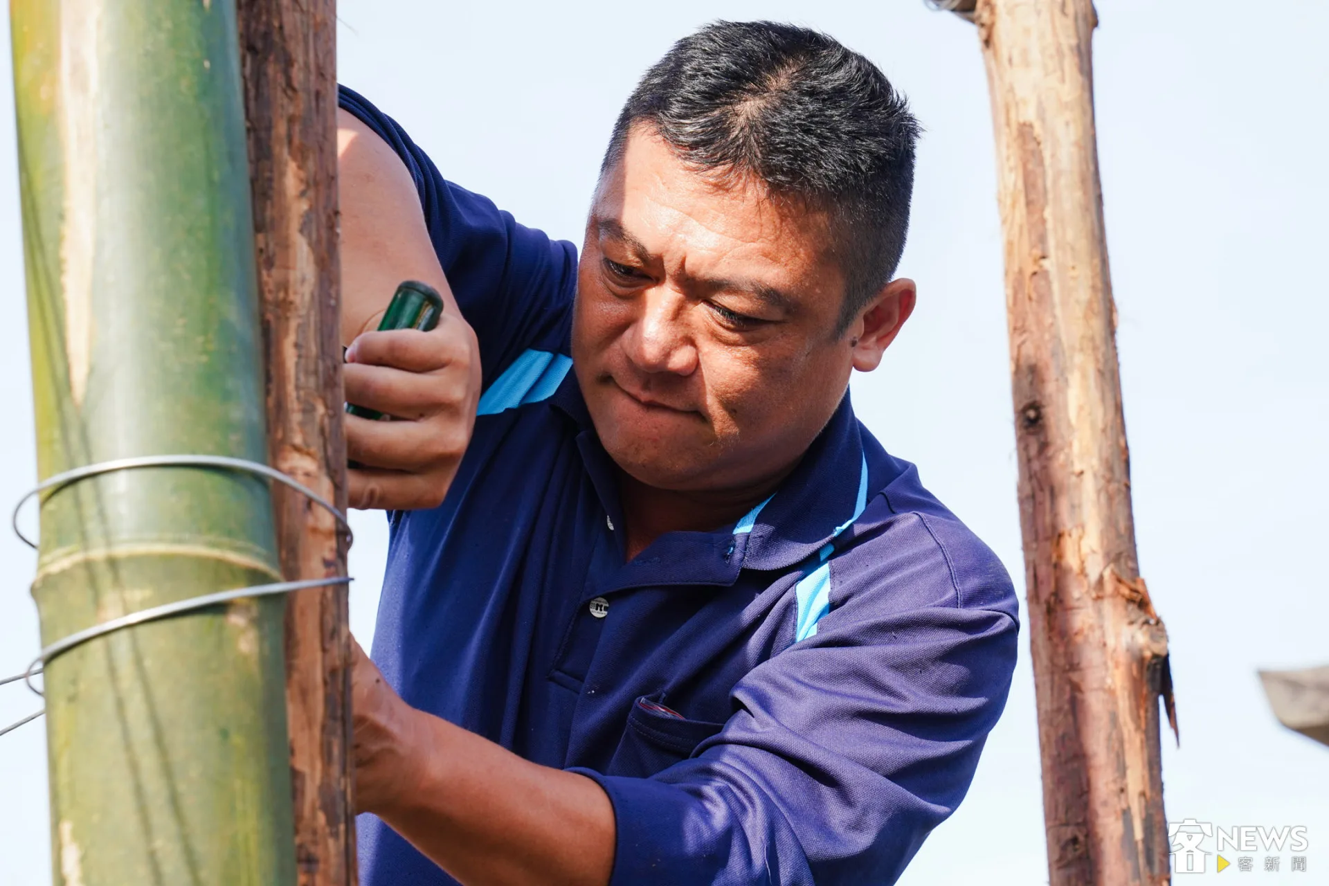 志工用鐵絲把竹子牢牢的固定在支架上。朱愷元攝