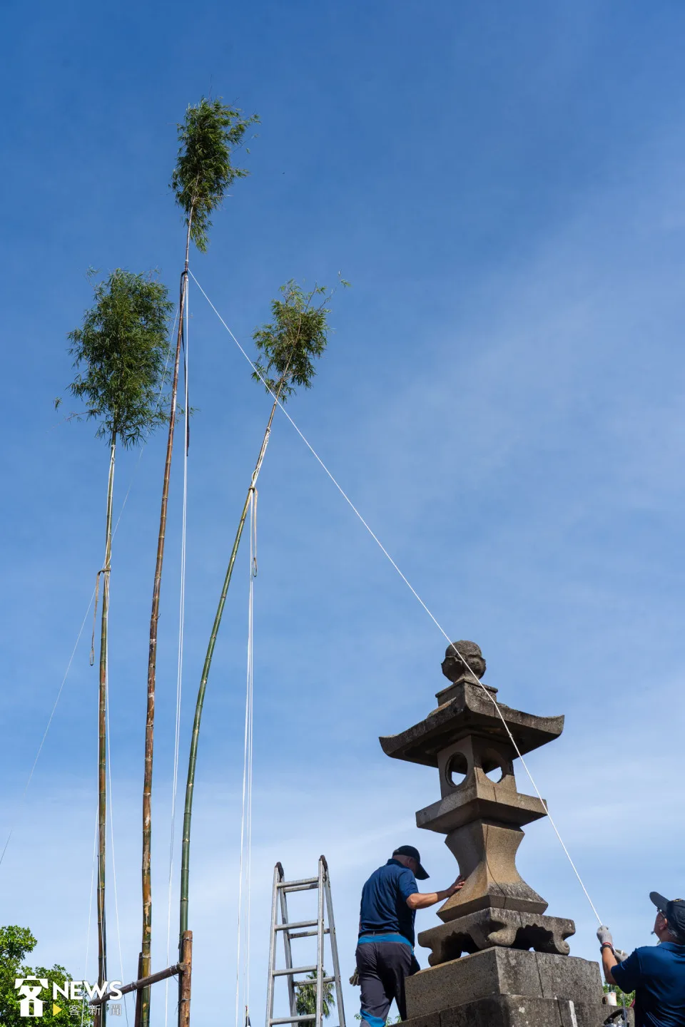 志工綁上固定竹身的繩索,拉向廟前左右兩側的石燈。朱愷元攝