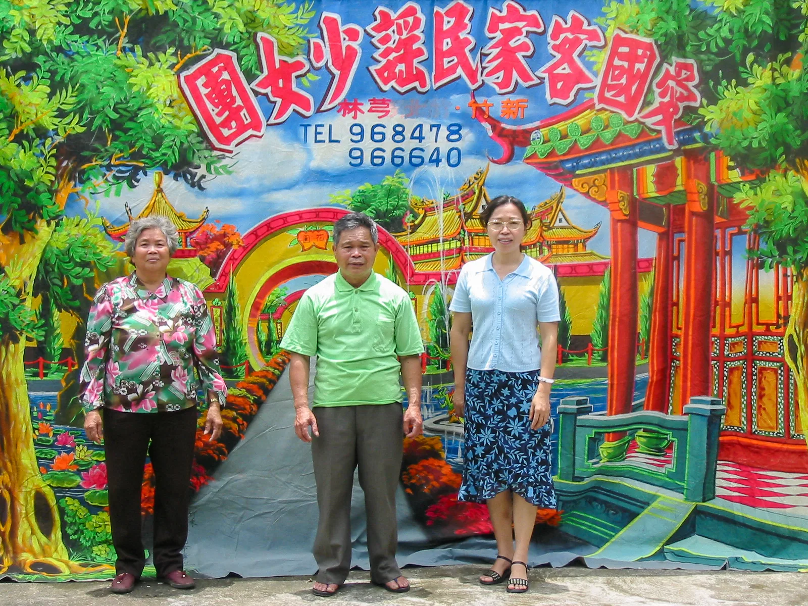 2003年6月11日山歌后陳淑姬(右)專訪林德富先生(中),在老屋禾埕布景前與林德富夫妻合影。陳淑姬提供