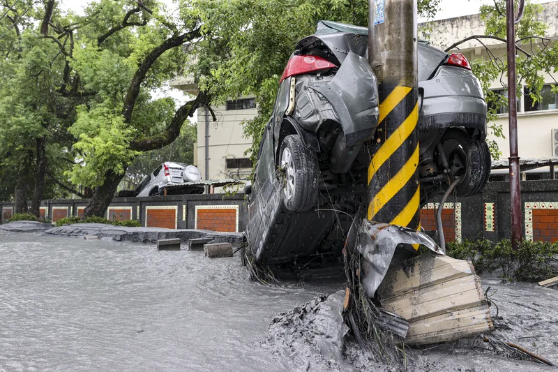 花蓮馬太鞍溪堰塞湖23日溢流，洪水沖斷橋梁，挾帶泥沙、石塊進入光復鄉市區，有車輛隨著泥水漂流後卡在電桿上。中央社