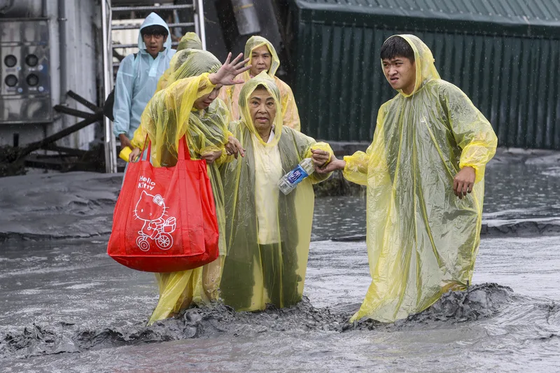 花蓮馬太鞍溪堰塞湖溢流，洪水沖斷橋梁，光復鄉部分地區淹水災情嚴重。圖為24日光復鄉居民穿著輕便雨衣涉水撤離。中央社