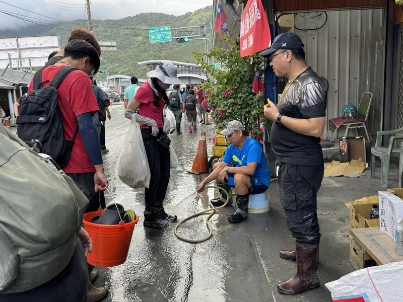 各地「鏟子超人」前進花蓮光復地區協助災民清理家園,30日有受災戶在車站前免費幫志工清洗雨鞋。中央社