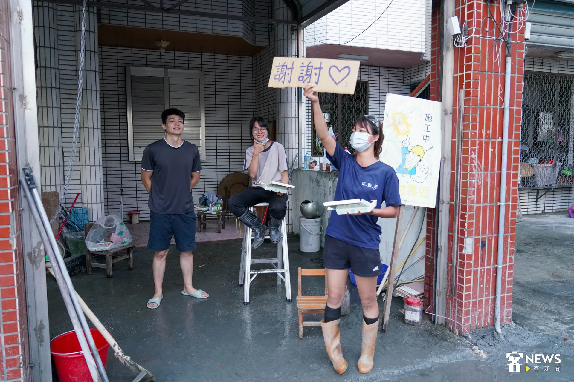 郭冠易的兩位小姨舉起簡單的紙板，向路過的志工致意。范修語攝