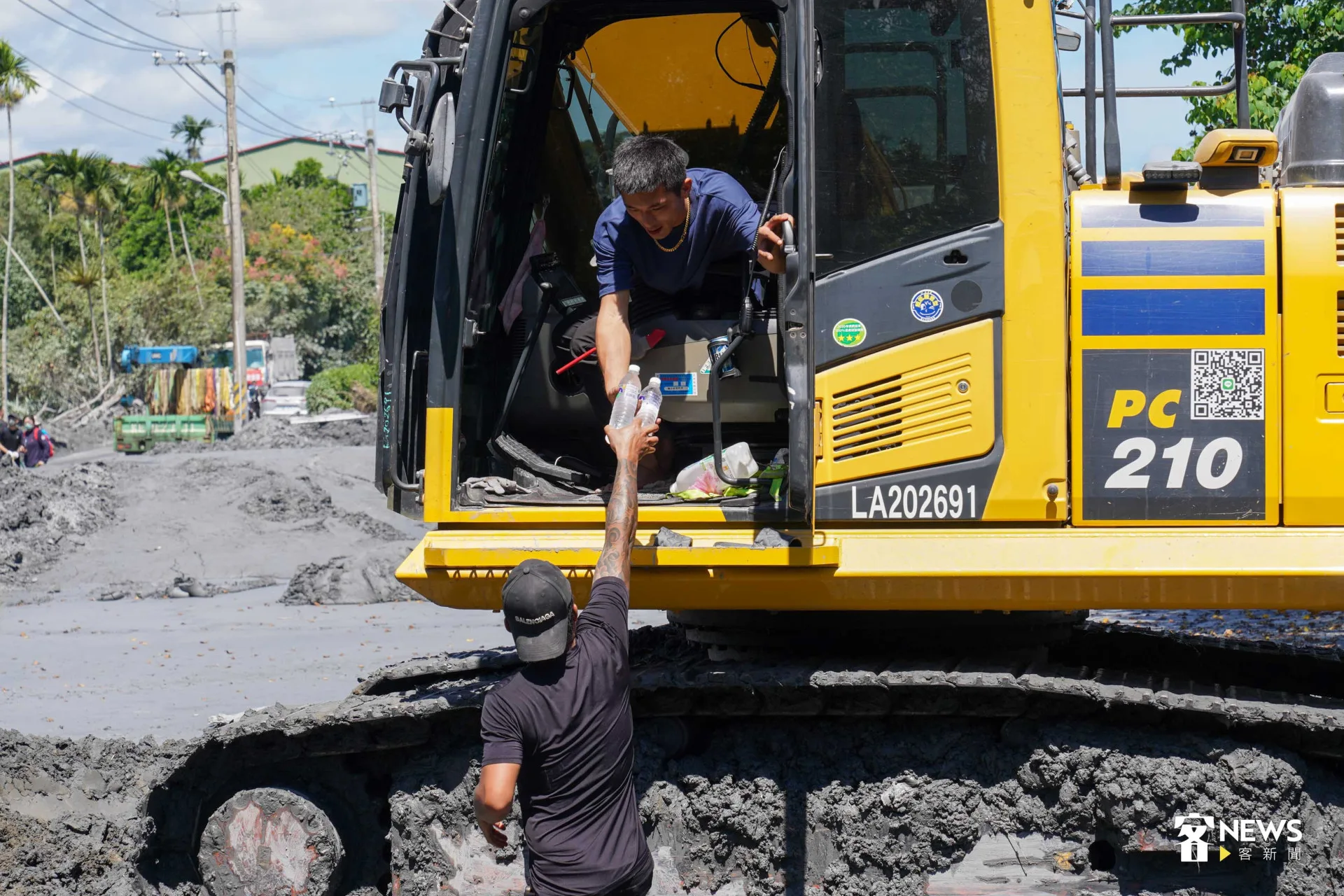 志工為怪手司機遞上冰水消暑。李台源攝