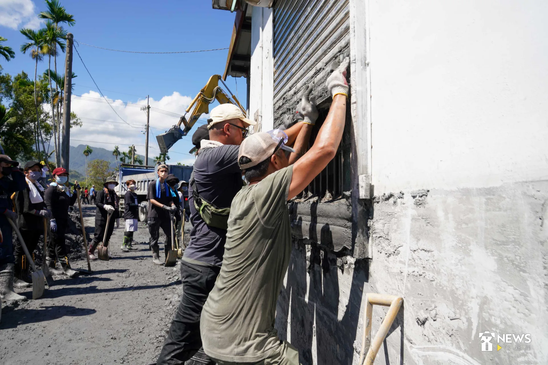 志工合力推開承載泥濘重量的鐵捲窗。李台源攝