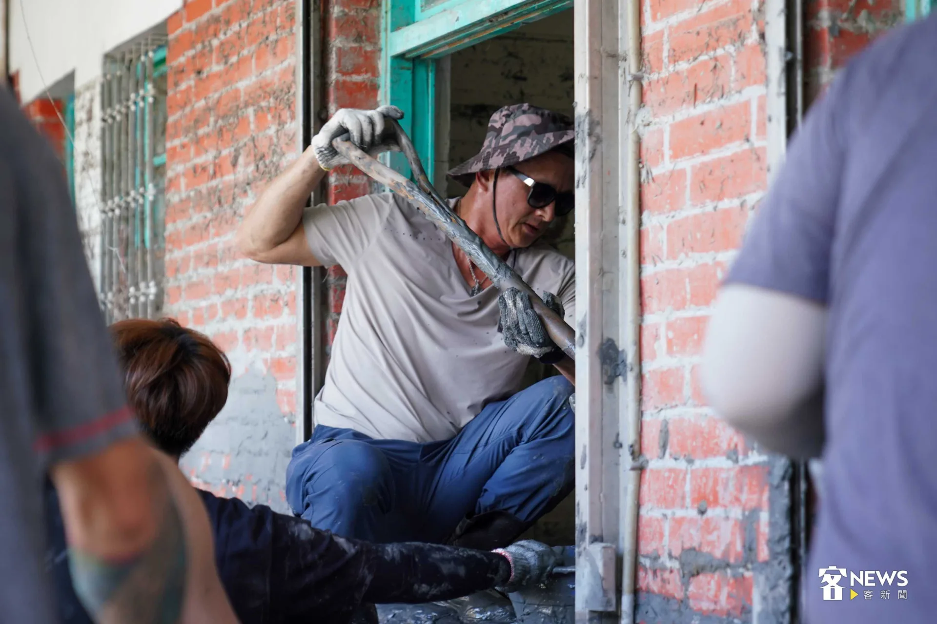 志工站在窗台上，將屋內的泥巴耙出。李台源攝