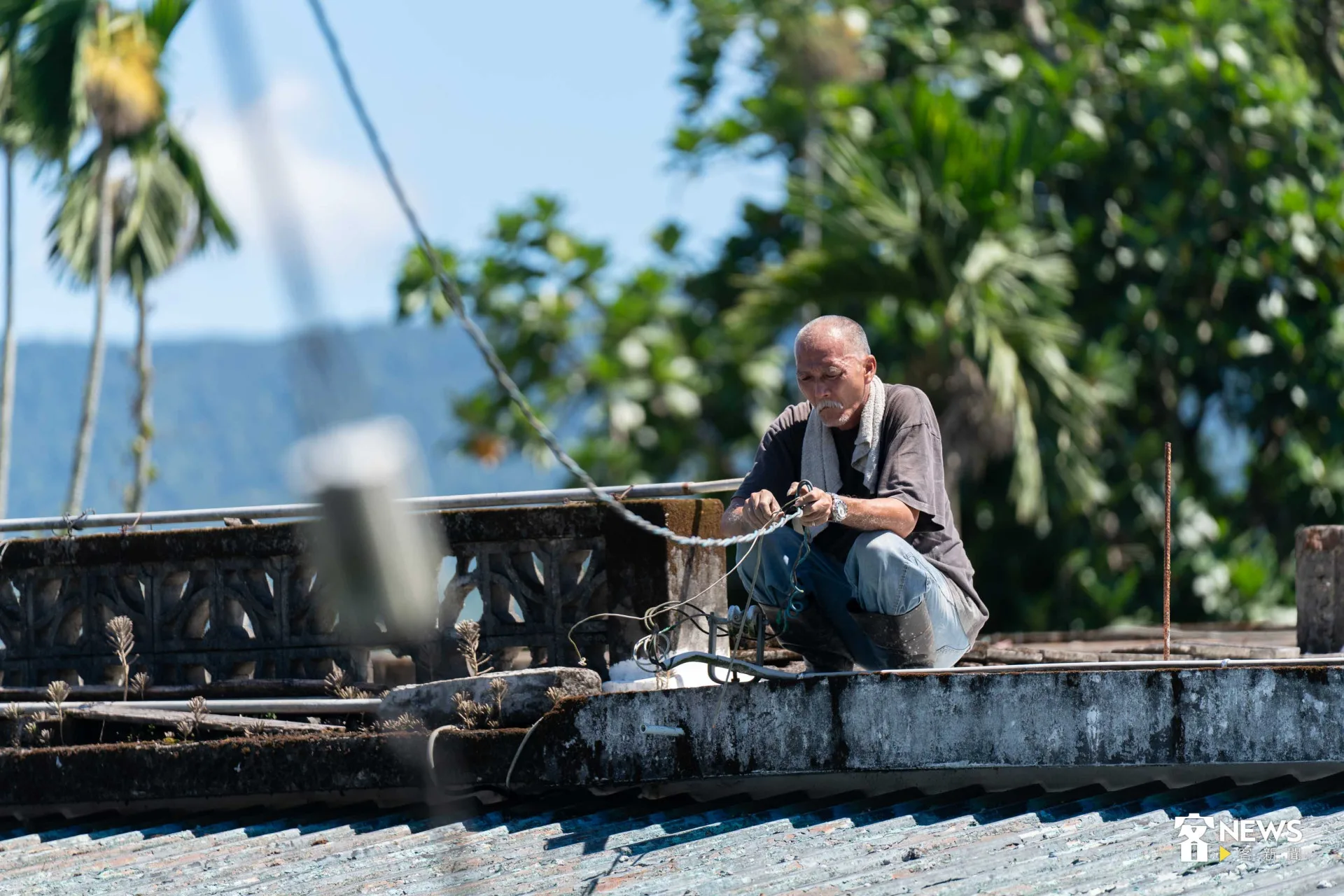 胡國勇站上屋頂，清除卡在道路中間的電線。范修語攝