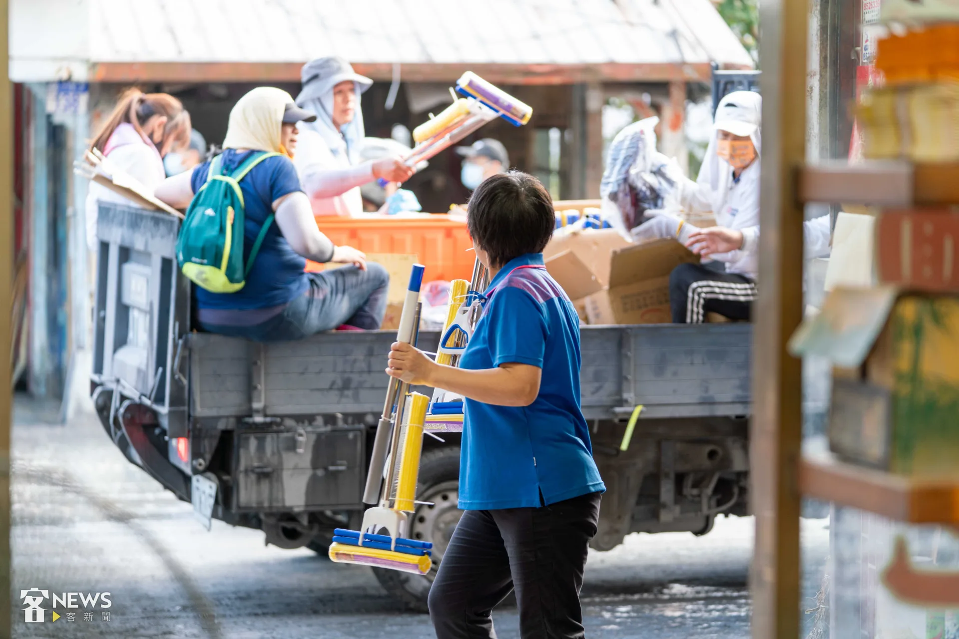 發放物資的車輛經過，黃銘漳太太趨前拿了幾支拖把。李台源攝
