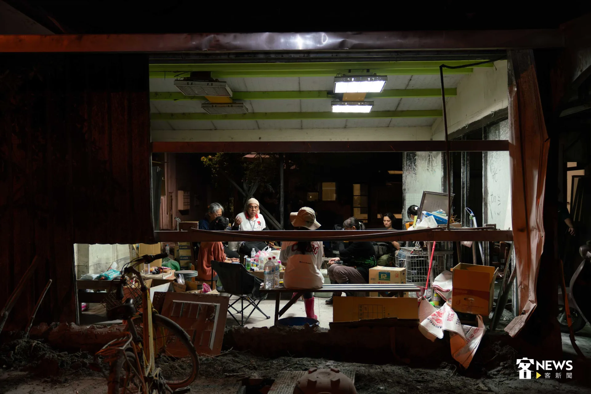 眾人圍坐門窗毀壞的室內。李台源攝