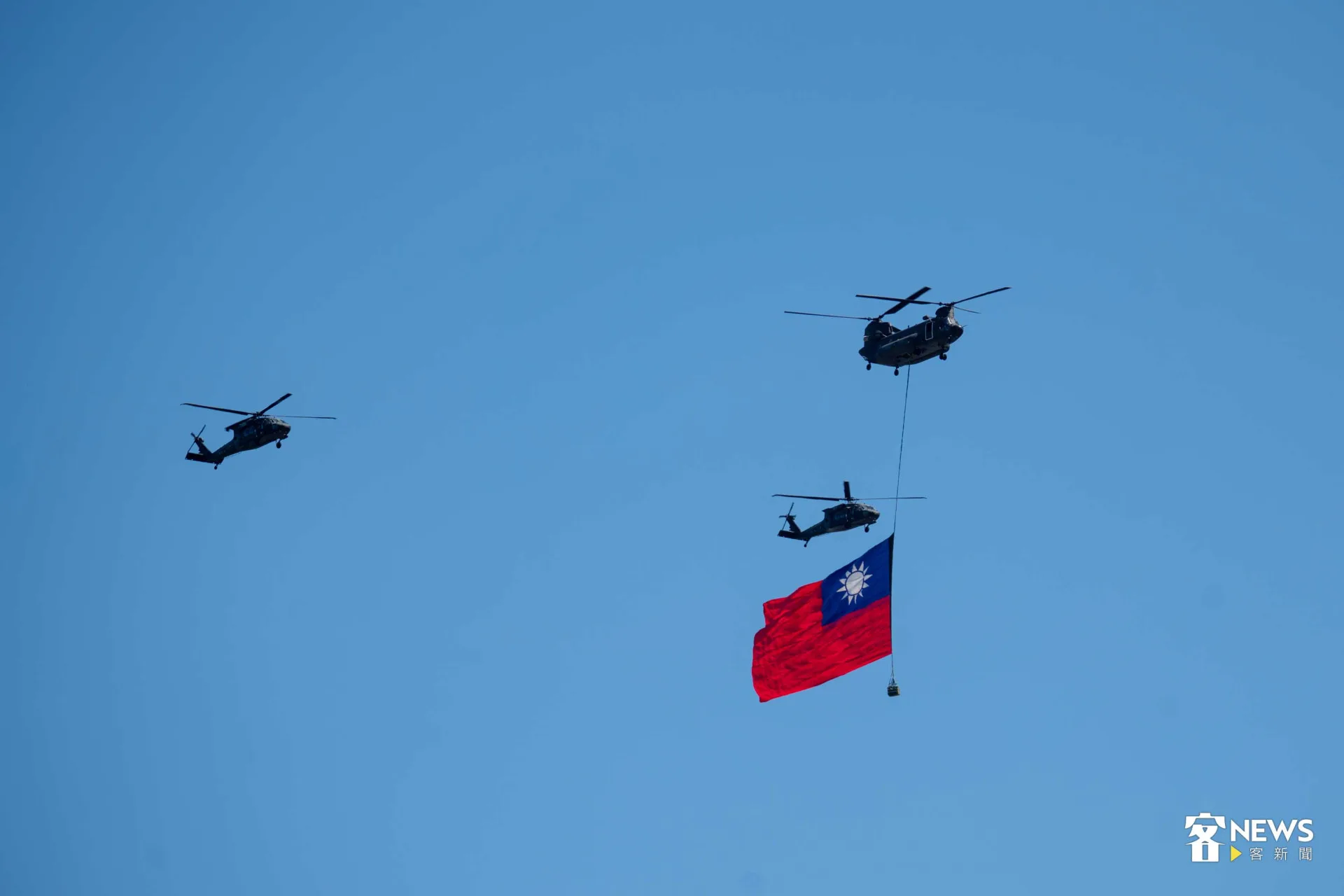 CH-47SD直升機吊掛巨幅國旗,伴隨2架UH-60M黑鷹直升機飛越總統府前方。范修語攝