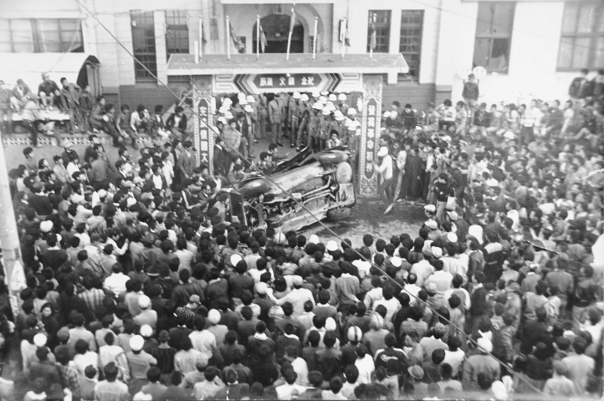 1977年11月19日，上萬的群眾下午四點包圍中壢警察分局，在分局前築成人牆的警員，眼睜睜看著偵防車被翻倒。 當時的張富忠就在分局對面的三樓，用相機記錄中壢事件過程。張富忠攝影／提供