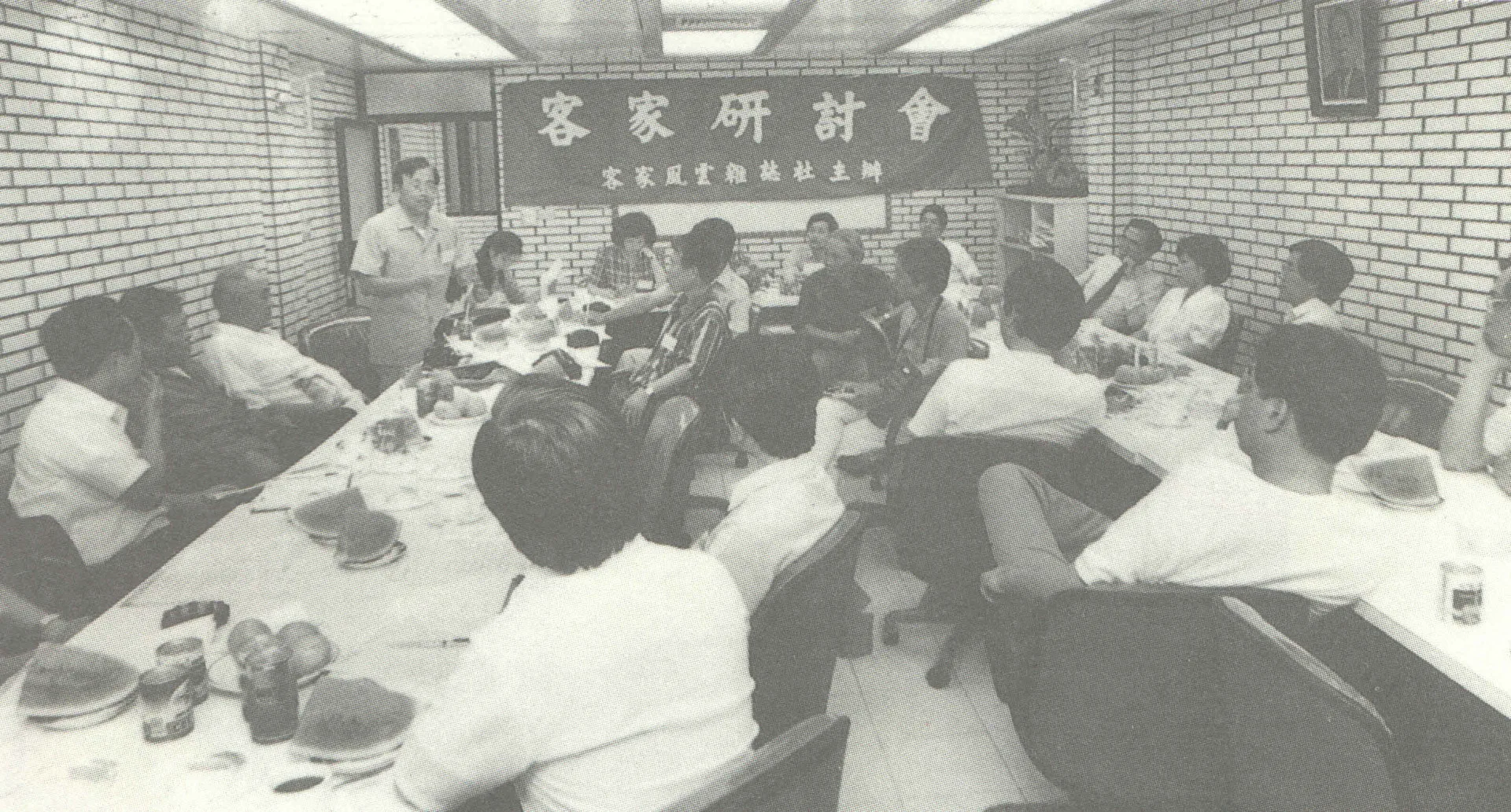這個會叫做「台灣四十年來客家研究第一次大集結」的客家研討會，討論客家學的建立。1989年5月21日星期日，在台北市徐綜合醫院三樓會議室。林一雄老師是主辦單位《客家風雲》雜誌代表(右前方坐在第一位置)，站立發言的是陳運棟校長(客家研究學者)，這張照片大約有一半的人已經成仙了，另外吊在右邊牆上的照片就是我們的少棒之父徐傍興博士。1989，台北，楊國鑫提供