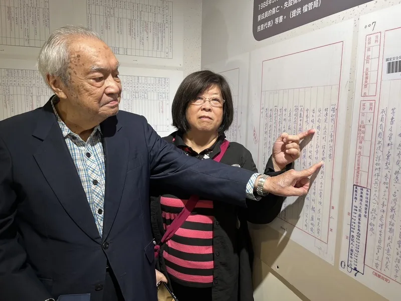 台北市二二八協會榮譽理事長黃秀婉（右）說，知道拂塵專案的人不多，並與同為受害者家屬徐世雄（左）一起在寫有自家受害長輩姓名的文件前合影。中央社