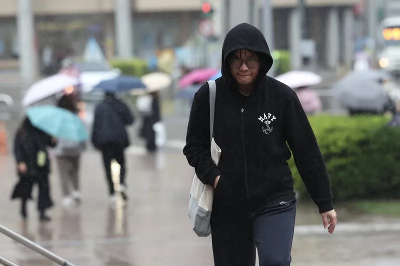 元旦起強冷空氣南下、愈晚愈冷，持續影響至1月4日清晨，平地低溫降至攝氏7度以下。新北市淡水區31日降下綿綿細雨，民眾將外套的帽子戴起遮雨。中央社