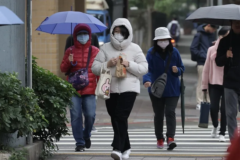 氣象署發布低溫特報，受強烈大陸冷氣團及輻射冷卻影響，18縣市下午至明晚留意攝氏10度以下低溫發生。圖為台北市大安區民眾穿羽絨衣並戴口罩保暖。中央社