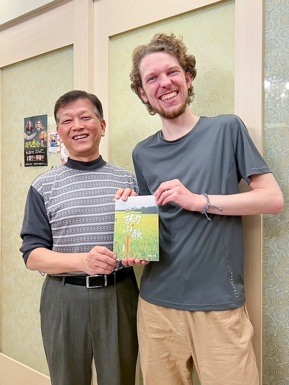 我送富盛敦（右）一本研究客家山歌的著作《詏山歌：台灣客家歌謠與文化》，他是笑開懷。2025，竹北，楊國鑫提供