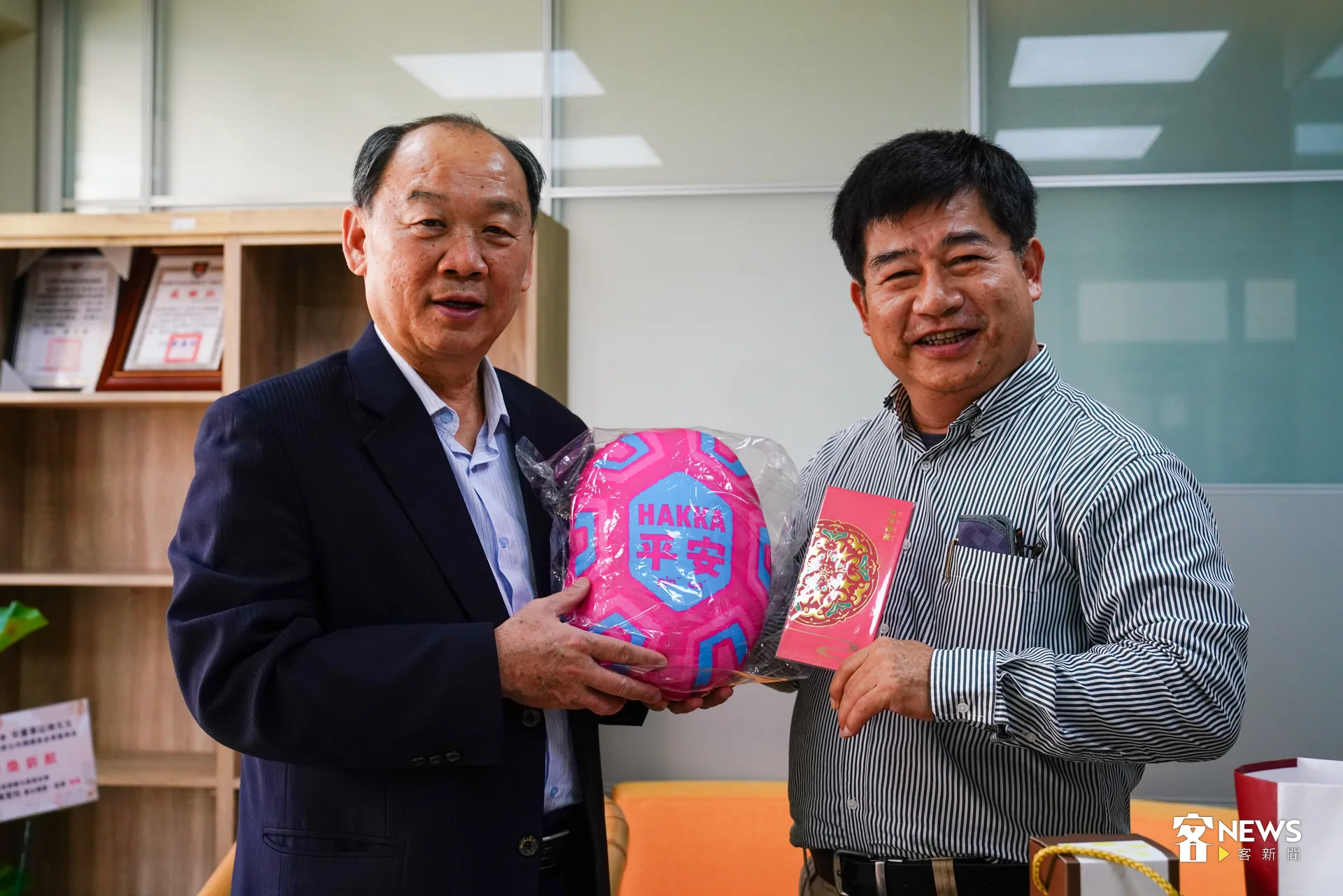客家文化發展中心主任謝勝信（左）致贈HAKKA平安抱枕、「五福臨門」紅包袋給客傳會董事長宋廷棟（右）。洪藝晅攝