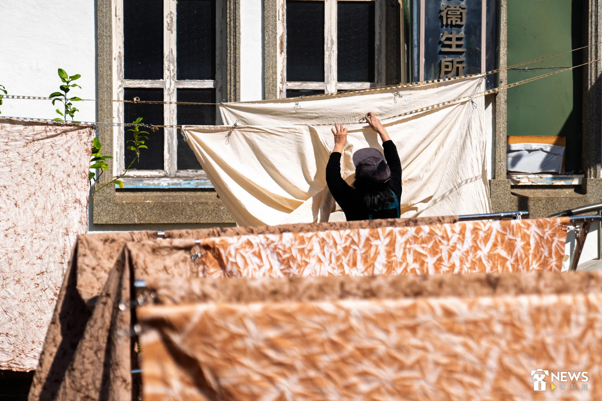 新埔柿染坊店面外的空地上，冬日暖陽正灑下，一匹匹柿染布料靜待時間洗禮。范修語攝