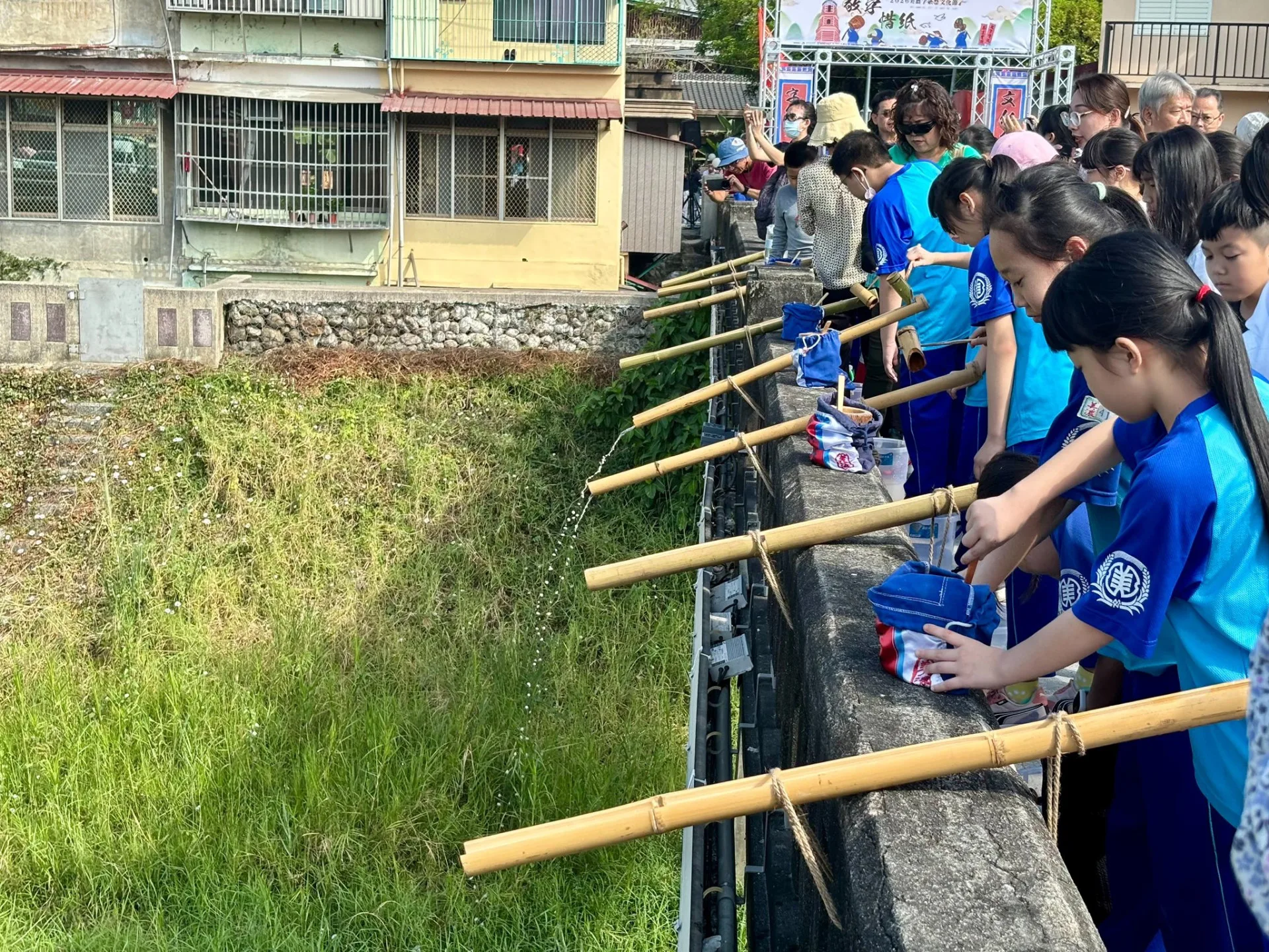 美濃國小學童舀字紙灰、舀一瓢水置於竹筒,流入美濃河中,完成送聖蹟儀式。美濃區公所提供