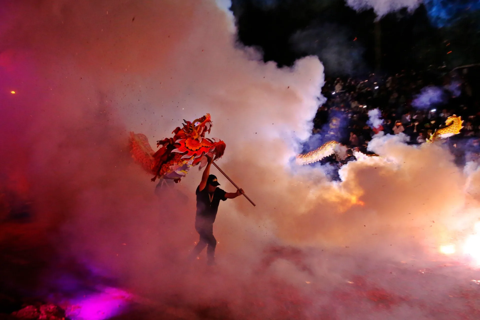 舞龍隊伍在鞭炮四射的煙霧中穿梭，猶如在雲霧中飛翔。苗栗市公所提供