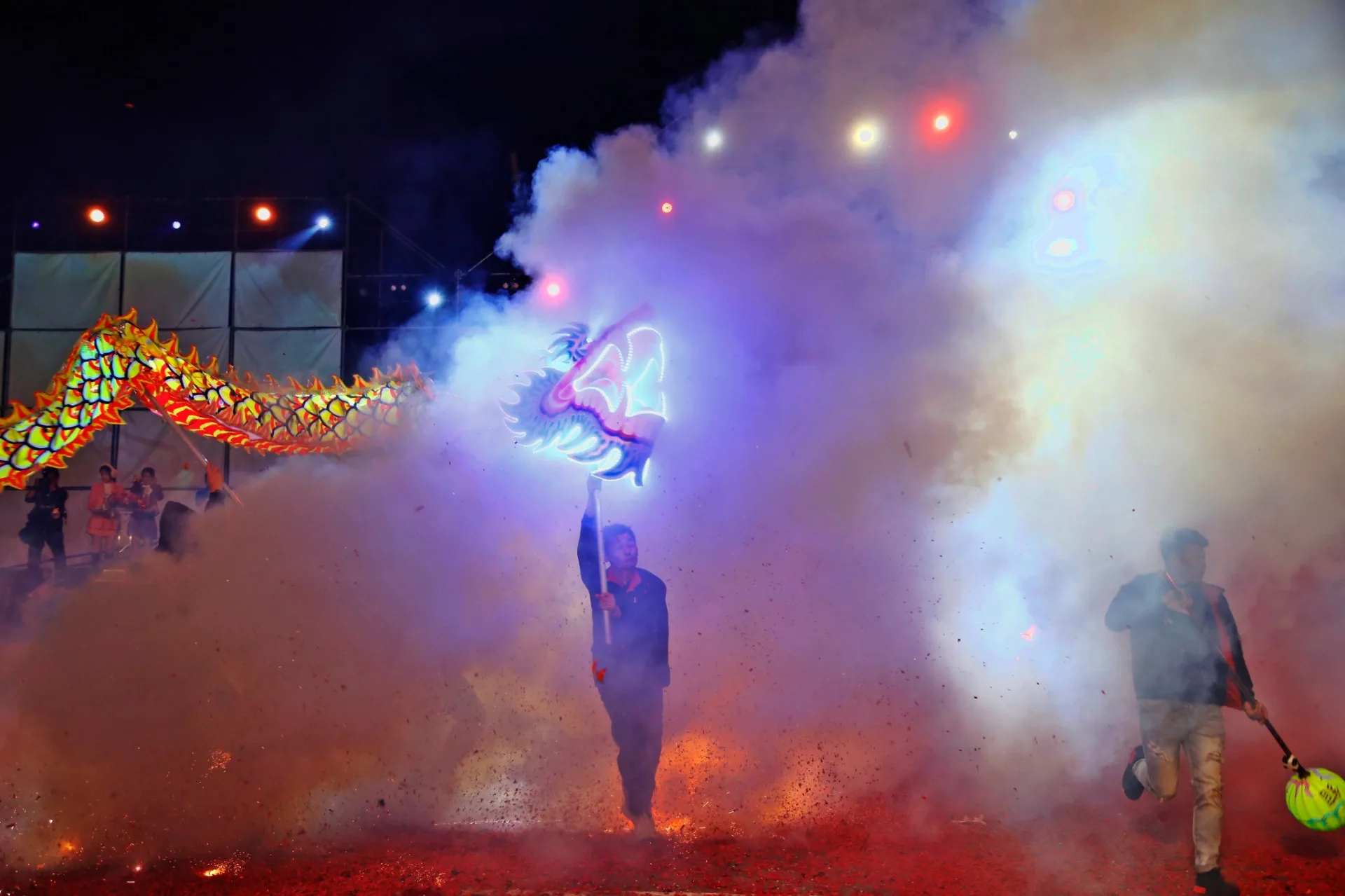 舞龍隊伍在鞭炮四射的煙霧中穿梭，猶如在雲霧中飛翔。苗栗市公所提供