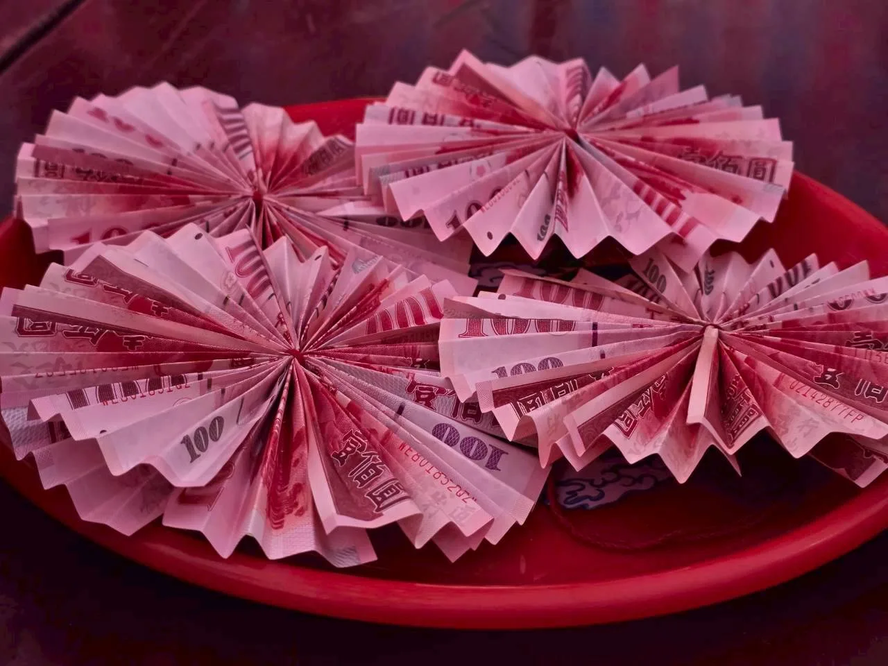 將新台幣摺成圓形，以紅繩掛在新丁頭胸前，象徵圓滿，稱為「結衫帶」。佳冬鄉公所提供