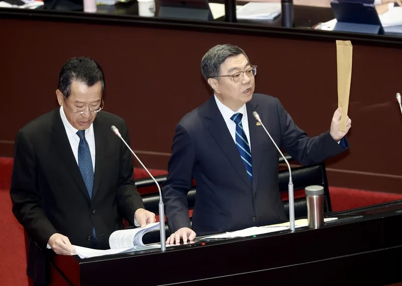 立委質疑行政院長卓榮泰包機前往日本觀看世界棒球經典賽引發爭議，卓榮泰（右）10日在立法院拿出一個牛皮紙袋表示，所有的單據連遊覽車的錢、門票的錢、單據都有，一塊錢都沒有報公費。中央社