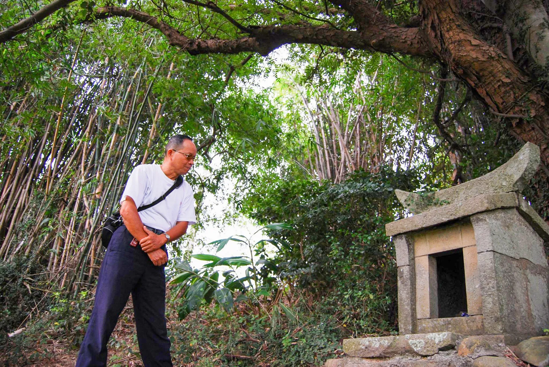 北埔山林深處的石板伯公，與古木、石砌護坡共存百年。簡樸的祠形，正是早期客家先民與自然共生的信仰樣貌。吳慶杰提供