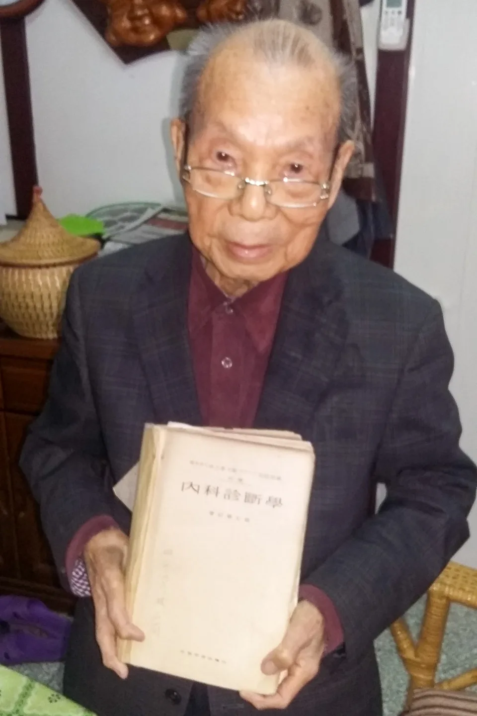 謝春梅是日治末期通過乙種醫師考試及格的醫師，圖為他生前拿著自習的內科診斷學書籍。何來美攝