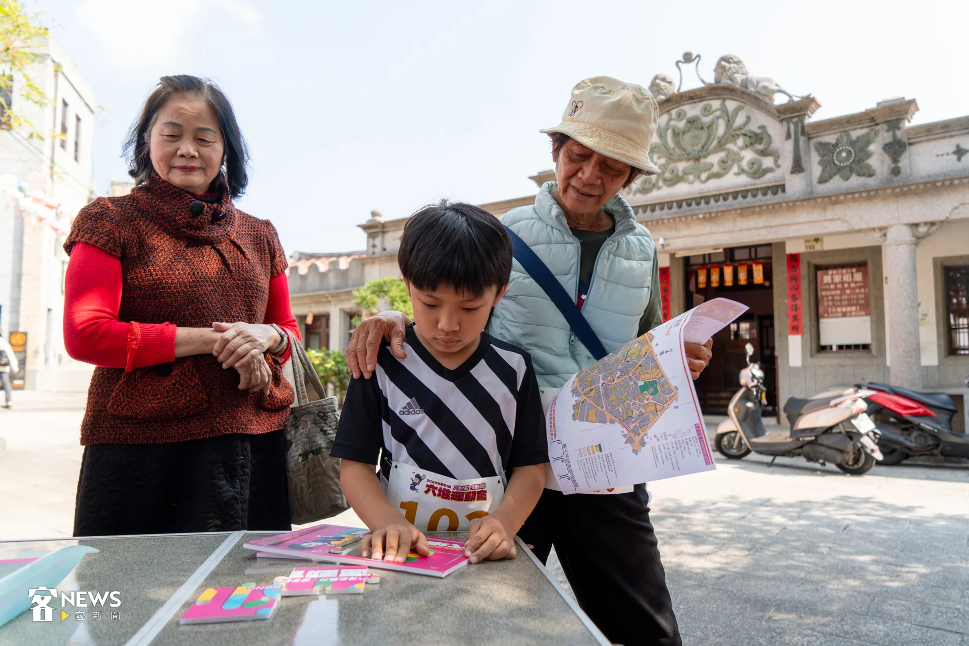 來自萬巒先鋒堆的邱志香(右),今天帶著6歲孫子(中)一起參加。圖為在蕭家古厝前拼拼圖破關。洪藝晅攝