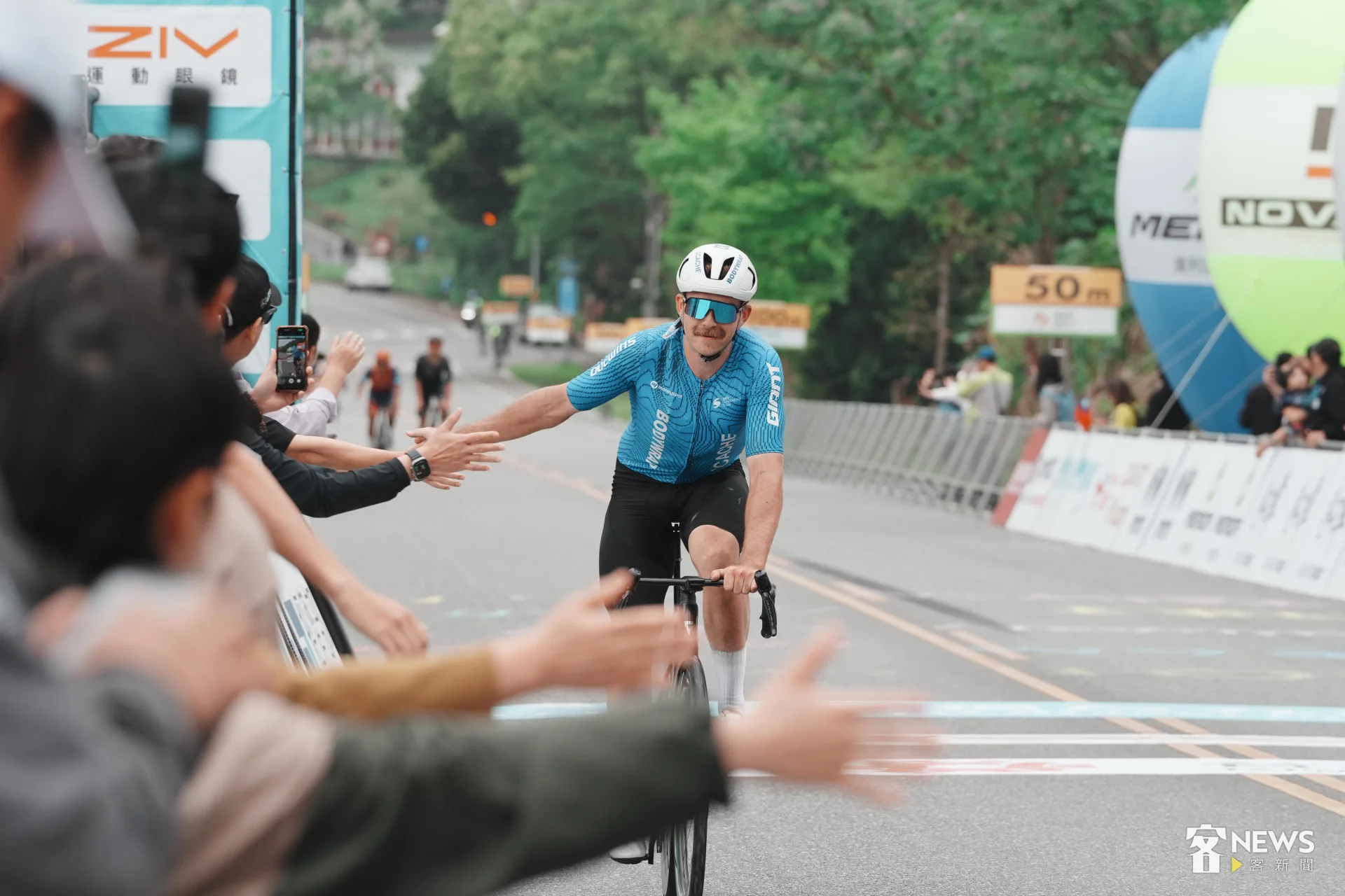 落後的選手展現運動家風度,落後仍騎完成全程,並與場邊加油群眾擊掌。李台源攝