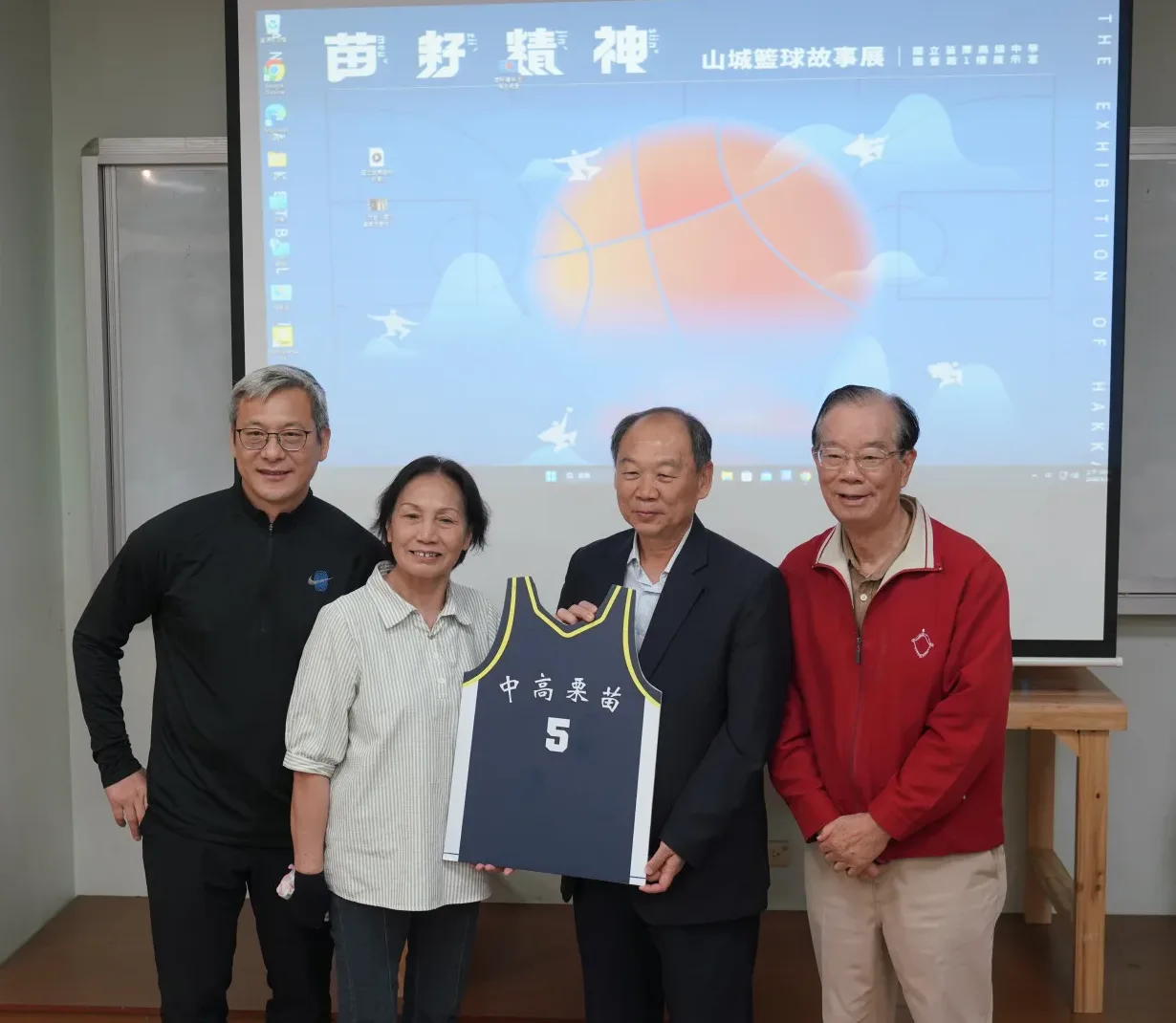 首屆HBL冠軍球隊成員(左/隊長黃萬隆、左2/林增福教練遺孀陳念慈、右1/助理教練陳雲錦)代表隊員王金城，捐贈球衣予客發中心謝勝信主任(右2)。